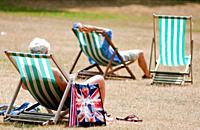 Visitors relax in the summer on deck chairs, St James park, London, UK