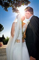 Newlyweds kissing against the sun