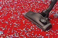 Hoovering coloured confetti spread over a red carpet, concept image of removing dust, cleaning, suppressing pollution and allergy