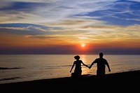 Romantic couple walking holding hands at sunset