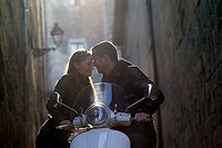 Couple embracing and leaning on a motor scooter