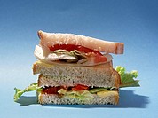 close view of a salad sandwich on a plain blue background