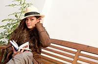 Fashionable girl with Panama hat reading a book outdoors