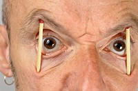 Close up of man keeping eyes wide open with match sticks
