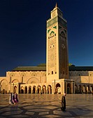 Moroccan man and women walking on the plaza of the Hassan II Mosque Casablanca at sunset, Morocco