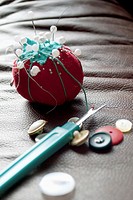 A tomato shaped pin cushion, buttons and seam ripper