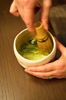 Preparation of Japanese matcha tea in a cup with a whisk