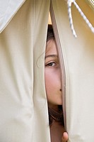 Young girl peeping through opening in a canvas tent