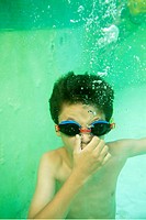 Young boy wearing swimming goggles and holding his breath underwater in a pool, Provence, France