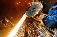 Close-up of heavy industry worker with grinding machine throwing a splash of sparks