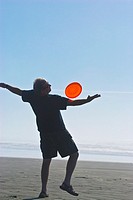 Man playing freestyle frisbee on California beach