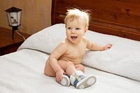 Happy Emotional Naked Ten Month Old Baby Girl Sitting on Bed