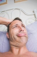 Man in his bedroom waking up and scratching his head