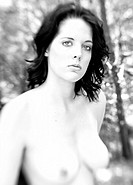 Black and White portrait of a partially nude nineteen year old brunette woman looking at the camera in a forest setting.