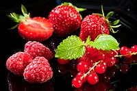 Strwaberries, raspberries and redcurrant on a black background