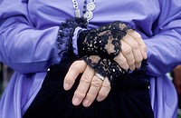Close up of a middle aged woman´s hands folded in repose, her costume that of the middle eighteen hundreds featuring black lace cuffs