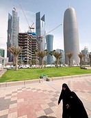 Women walking on The Corniche with modern office towers and skyline in business district in Doha Qatar