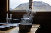 Hot soup steams from titanium camping pan in mountain hut, Kungsleden trail, Sweden