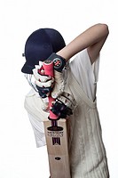 Young cricketer in protective helmet and gloves demonstrating a defensive shot