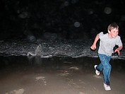 Young Boy running from wave