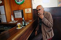 Rotterdam, Netherlands. Senior adult male drinking a beer while sitting at a bar down town Nieuwe Binnenweg.