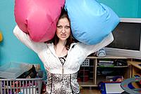 A weary young mum blocking out noise with children´s bean bags over her ears