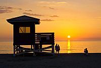 Life guard stand and people silhouetted aganist orange sunset sky over Gulf of Mexico from Venice Beach Florida