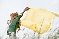 Young woman playing with yellow drape outdoors
