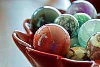 This stock image shows two white crosses reflected in a bowl of large, glass marbles  Background intentionally blurred for artistic effect