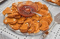 This traditional Norwegian food, is a silver platter of heart shaped waffles with slices of brown goat cheese on top  In the center of the platter is ...