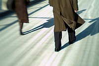 Man and woman walking separtely across the Millennium Bridge, London, England, Europe