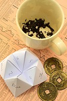 Where not to go for investment advice: Tea cup with tea leaves, Origami fortune teller - cootie catcher, Coins used with I-Ching laying on European fi...