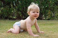 young baby girl with blonde hair age 9 nine months crawling on grass