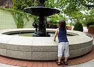 Small child leans on a water fountain to get a better look