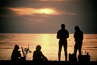 Two couples picnic on the beach watching the sun set and sharing food