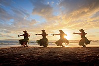 Four hula dancers at sunset at Palauea, Maui, Hawaii, backlit by the sun
