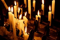 many lit candles in dark room in church