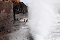 girls playing at the beach and have fun with the spray of waves, Madeira, Portugal, Europe.