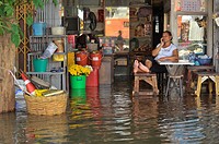 chinese lady talking on mobile phone whilst her shop is flooded, bangkok floodings, chinatown, bangkok, thailand