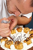 A pastry chef decorating a cake with whipped cream