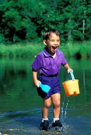 Afghan-American boy thrilled with water play in pond, summer, Midwest USA