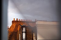 Chimneys on the top of a London´s building through the window and curtains