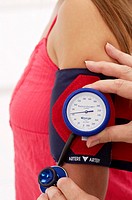 Young woman undergoing a blood pressure test with a blood pressure gage, no head, cropped picture