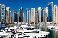View of high-rise modern building towers and yachts in Marina at New Dubai in United Arab Emirates