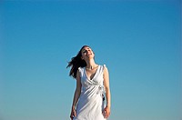 Portrait of a smiling young woman wearing summer dress against blue sky