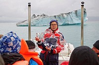 A guide explains glacial ice onboard a tour of Glacier Lagoon, Iceland