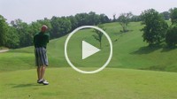 Golfer teeing off with driver onto fairway.