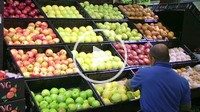 Man facing apples in grocery store.
