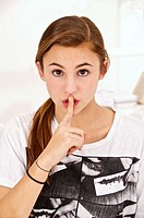 Young teenage girl putting her finger in front of her mouth
