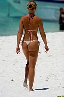 Young woman in thong bikini strolls on white sand beach Similan Islands Thailand